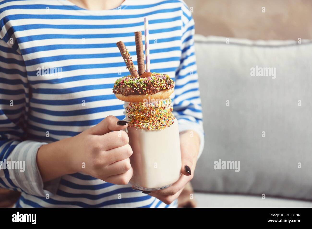 Fille tenant milkshake avec beignet et autres bonbons dans le pot Banque D'Images