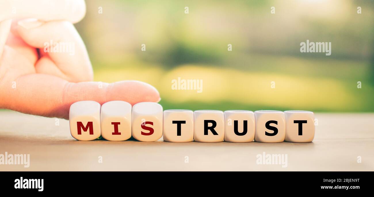 La main fait des dés et change le mot « Mistrust » en « Trust ». Banque D'Images