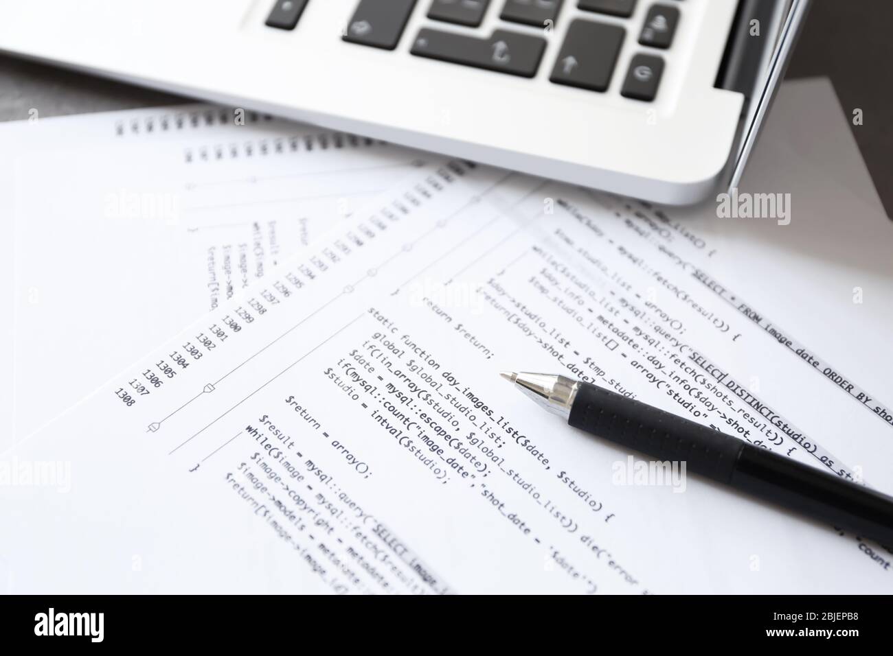 Code de script sur papier, stylo et ordinateur portable sur le lieu de travail du programmeur Banque D'Images