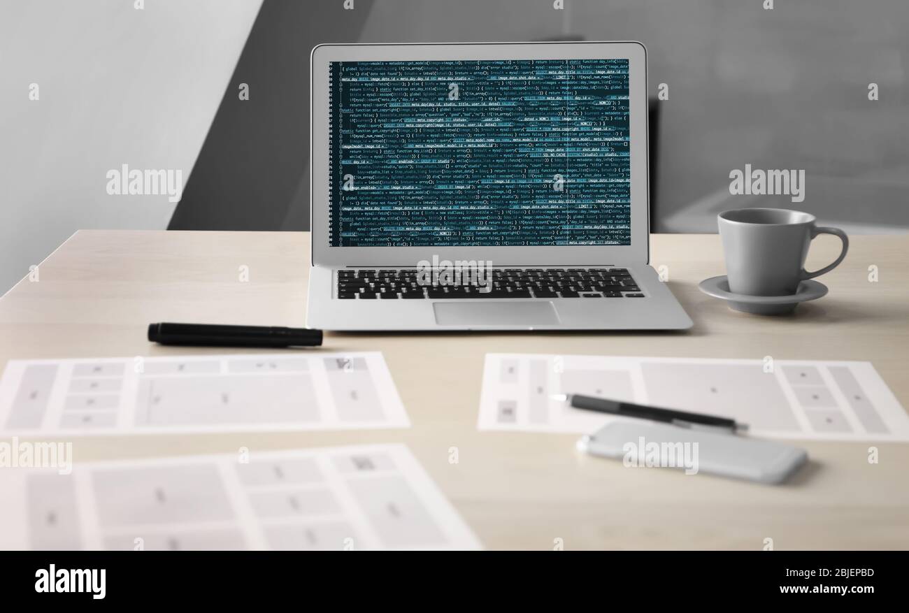 Lieu de travail du programmeur avec ordinateur portable, documents et tasse de café sur table Banque D'Images
