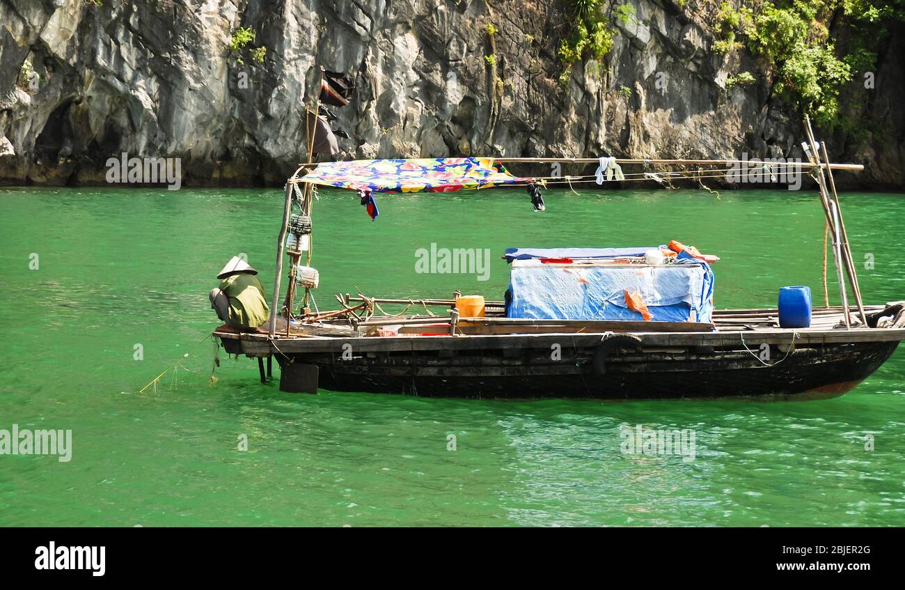 Pêcheur sur le bateau tirant hors du filet de pêche pour vérifier la présence de poissons. Baie de Halong, Asie du Vietnam, océan Pacifique. Banque D'Images