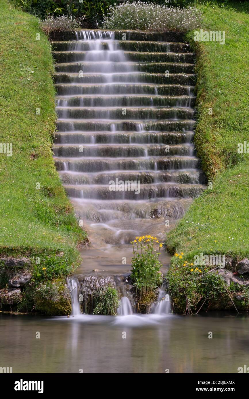 Longue exposition d'une cascade qui coule dans les escaliers dans un jardin ornemental Banque D'Images