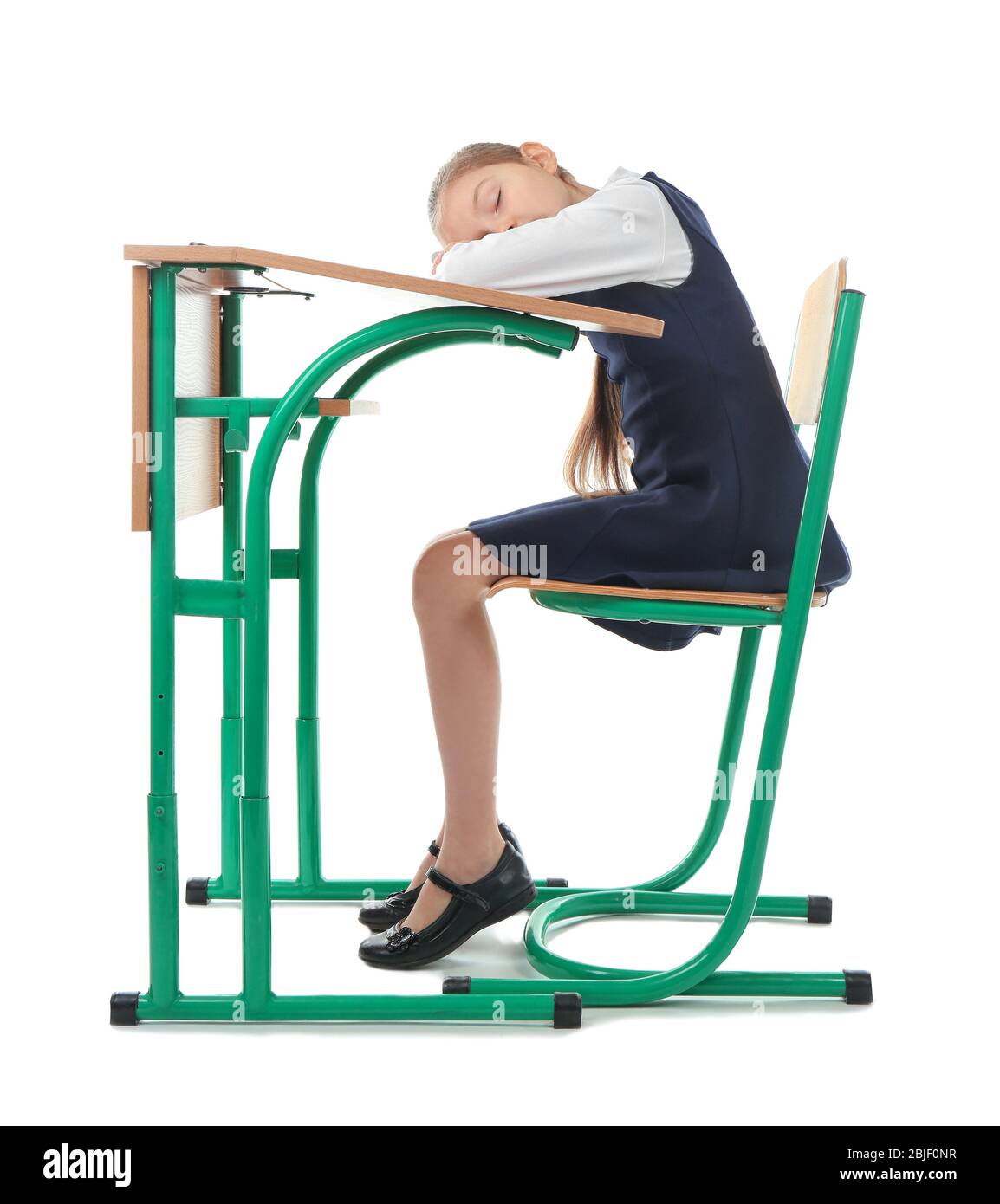 Concept de posture incorrect. Petite fille assise au bureau d'école sur fond blanc Banque D'Images