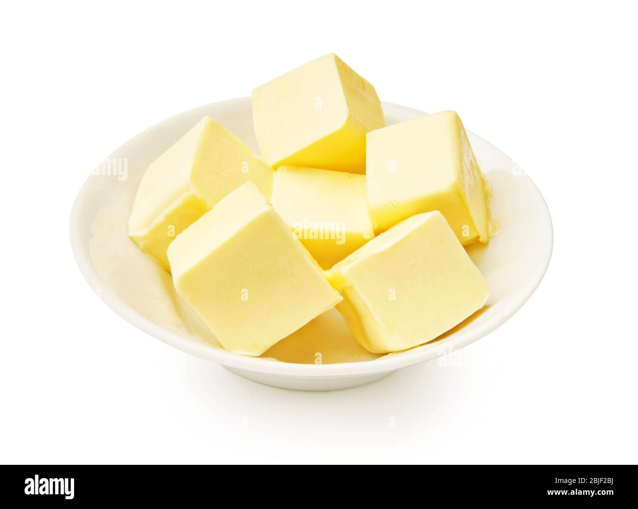 Morceaux de beurre dans un bol blanc isolé. Cubes de beurre. Banque D'Images