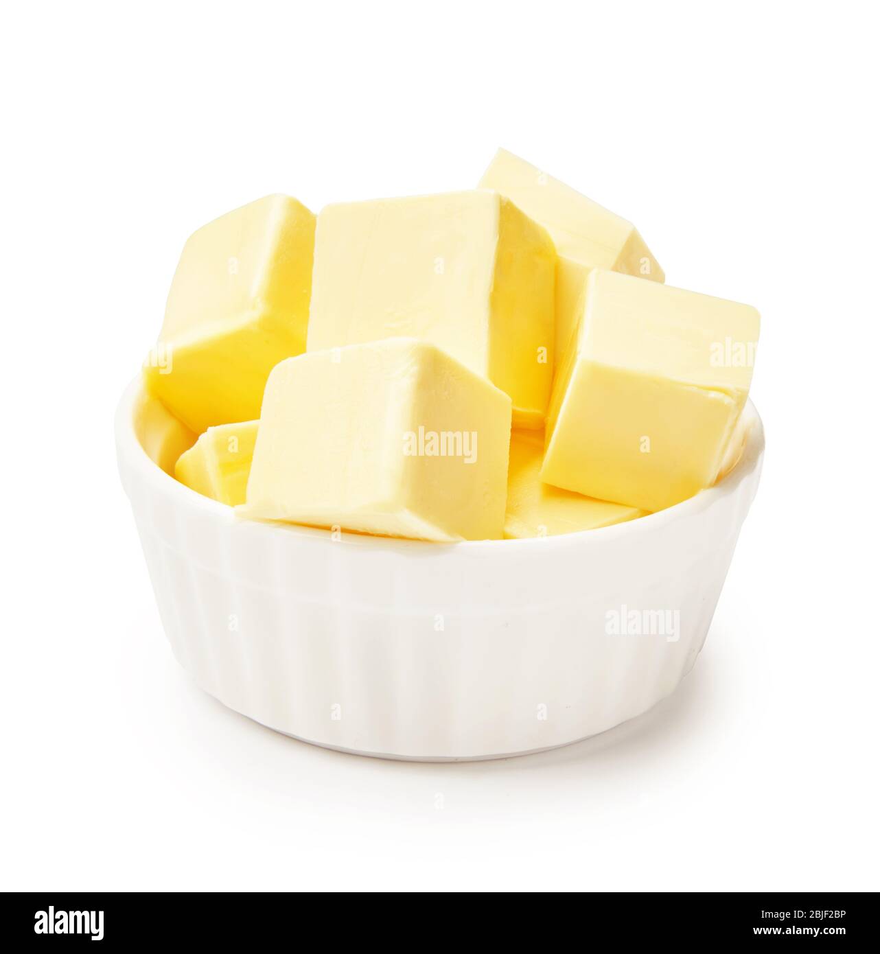 Morceaux de beurre dans un bol blanc isolés sur fond blanc. Cubes de beurre. Banque D'Images