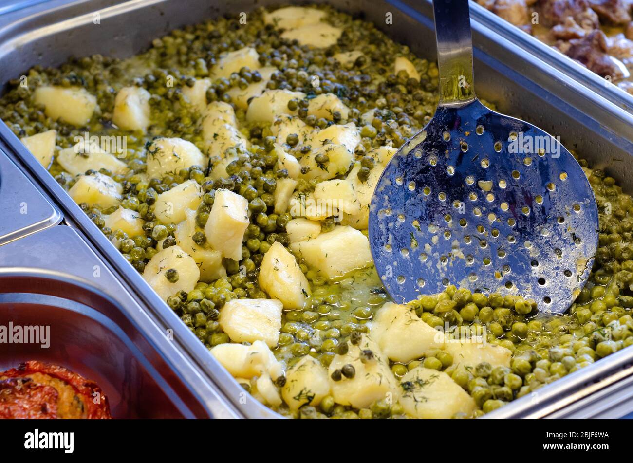 Cuisine méditerranéenne une poêle est placée pour la cuisson lente d'une poêle avec des pommes de terre rouges et des pois Banque D'Images