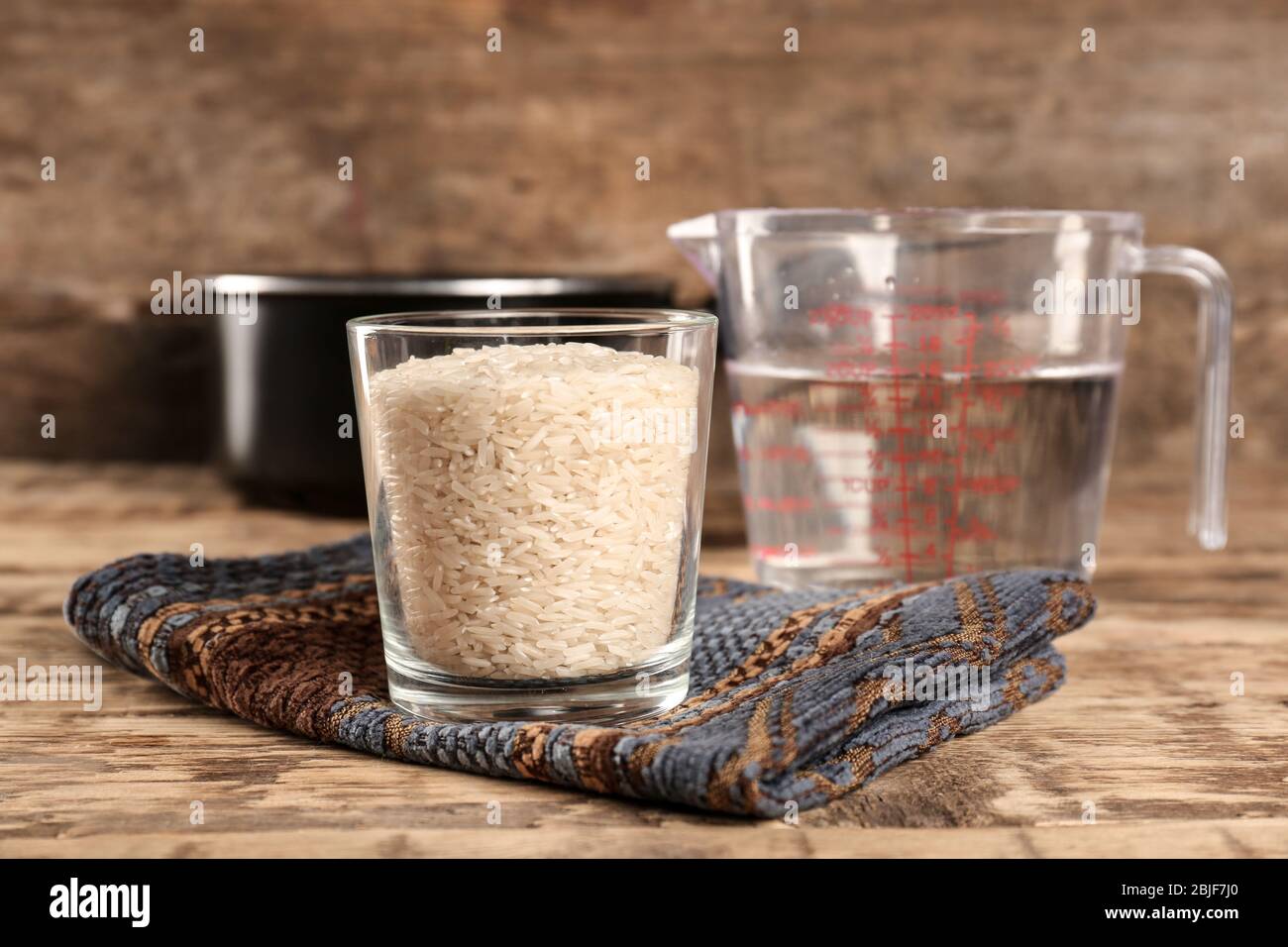 Verre de riz et pichet gradué avec de l'eau sur table en bois Photo Stock -  Alamy