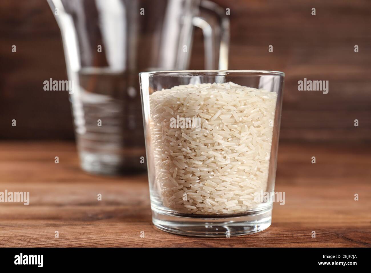 Verre de riz et pichet gradué avec de l'eau sur table en bois Photo Stock -  Alamy