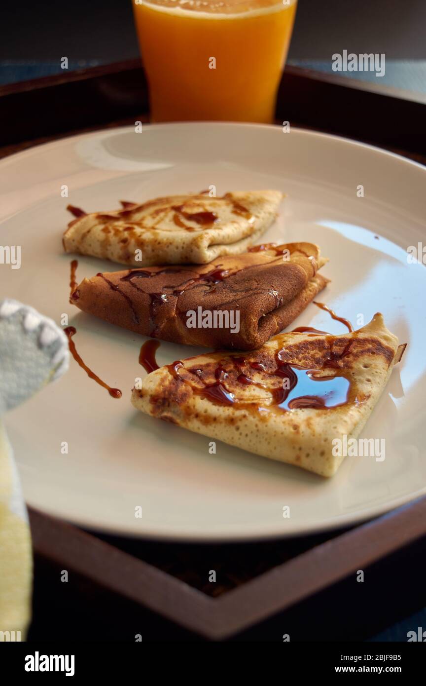 Mise au point sélective. Délicieux petit déjeuner avec crêpes et jus d'orange sur plateau en bois Banque D'Images