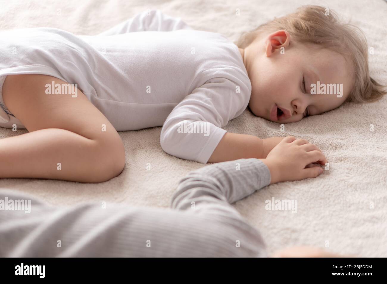 Enfance, sommeil, détente, famille, style de vie concept - deux jeunes enfants de 2 et 3 ans vêtus de body blanc et beige dorment sur un beige Banque D'Images
