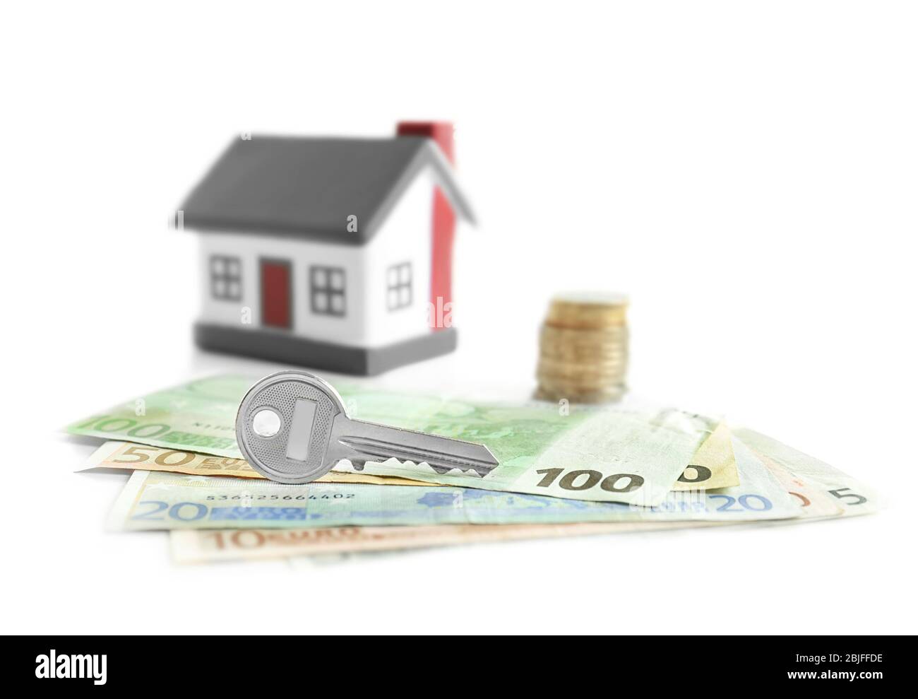 Clé avec argent et maison de jouets sur fond blanc. Concept de courtier d'assurance Banque D'Images