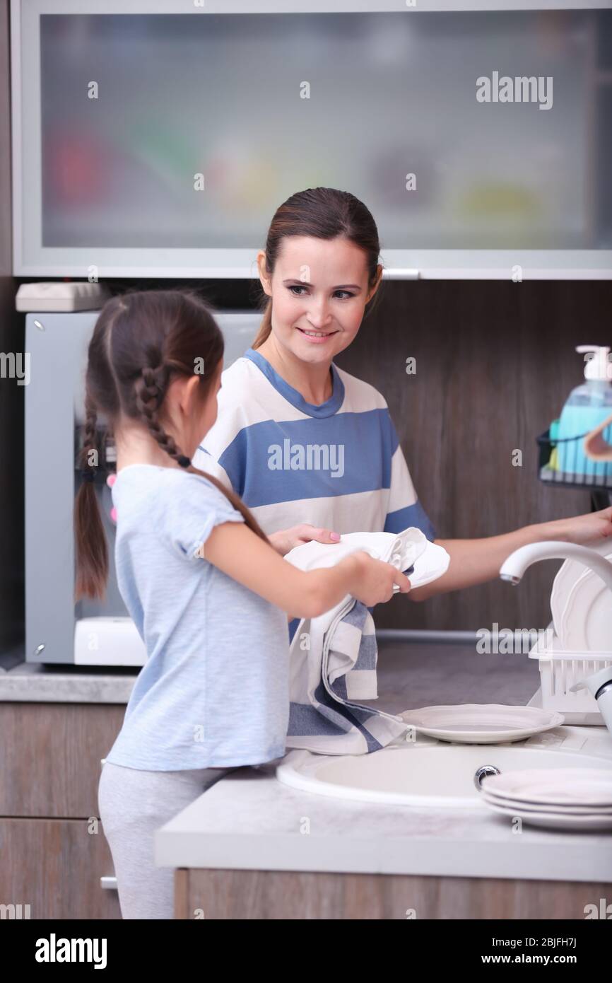 Fille aidant la mère laver des plats dans la cuisine Banque D'Images