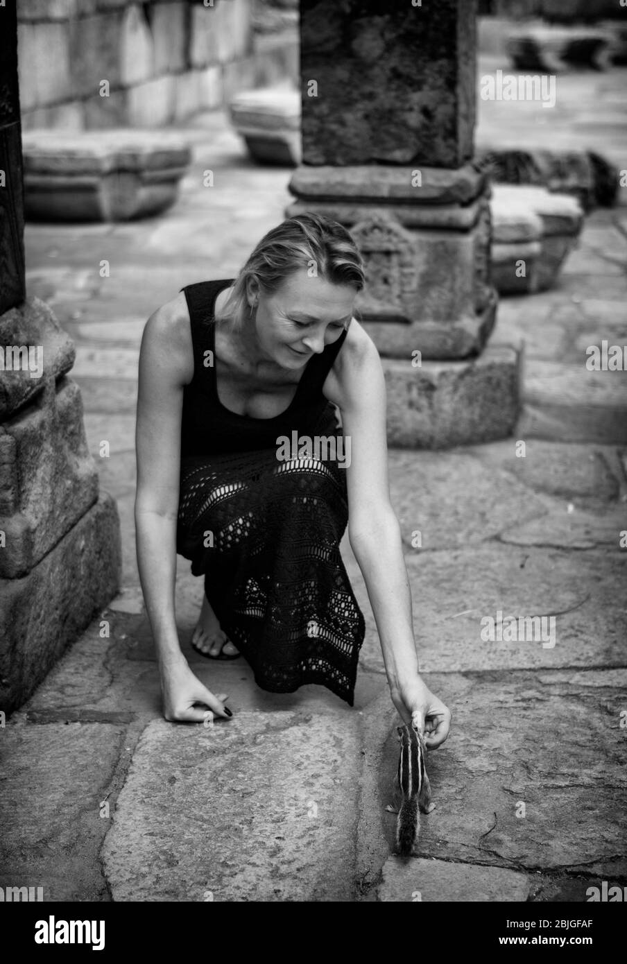 New Delhi / Inde - 21 septembre 2019: Femme de tourisme alimentant l'écureuil de palmier du nord (Funambulus pennantii) dans le complexe Qutb Minar, UNESCO monde HE Banque D'Images