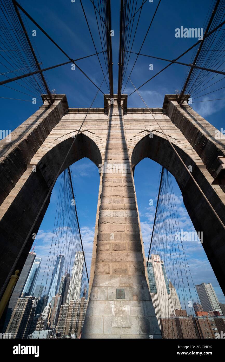 Vue abstraite grand angle regardant la tour voûtée gothique tenant le pont de Brooklyn avec des détails de câble traversant Banque D'Images