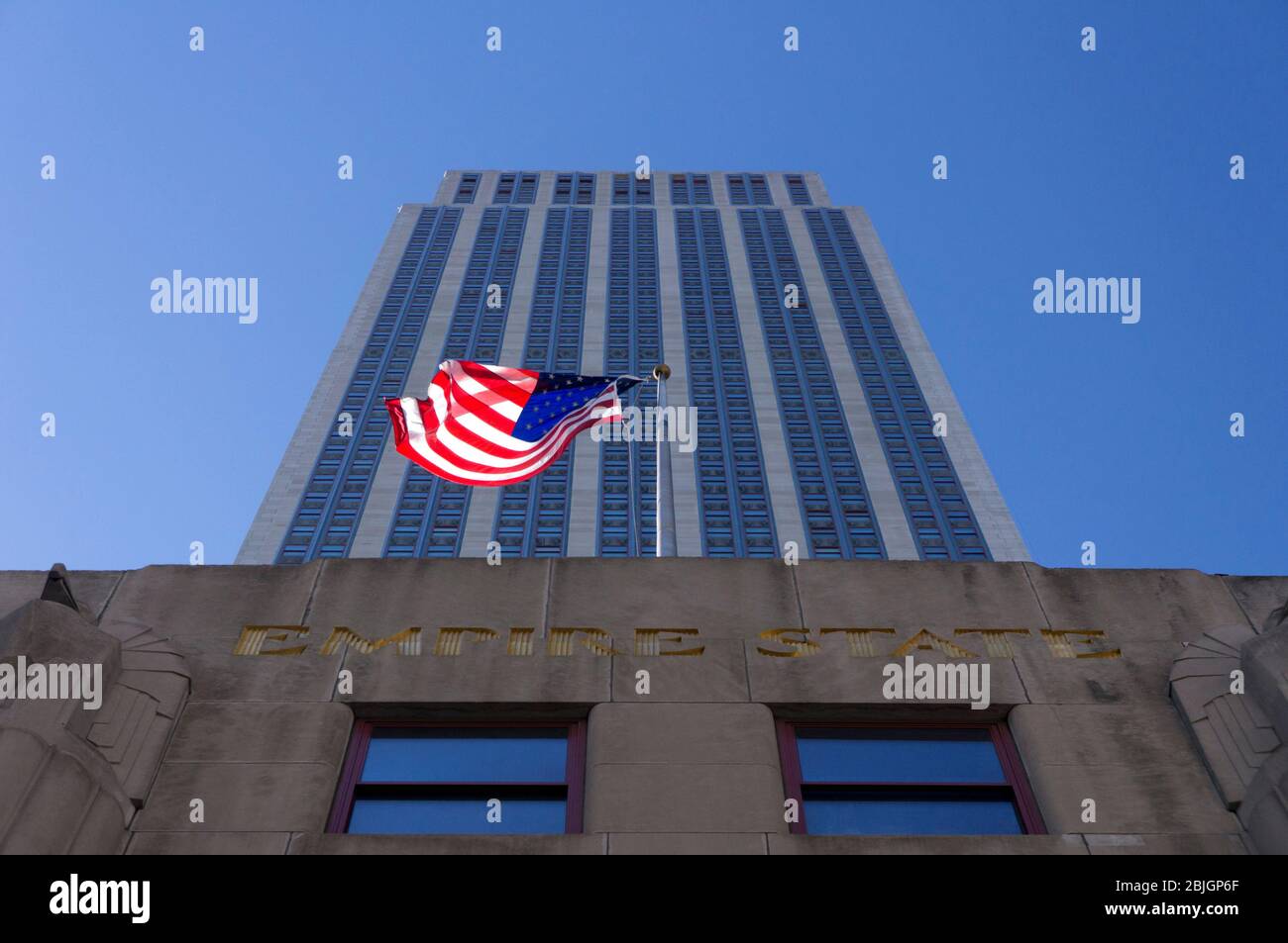 En regardant directement l'édifice historique de l'Empire State Building avec un drapeau américain en agitant à New York City Banque D'Images