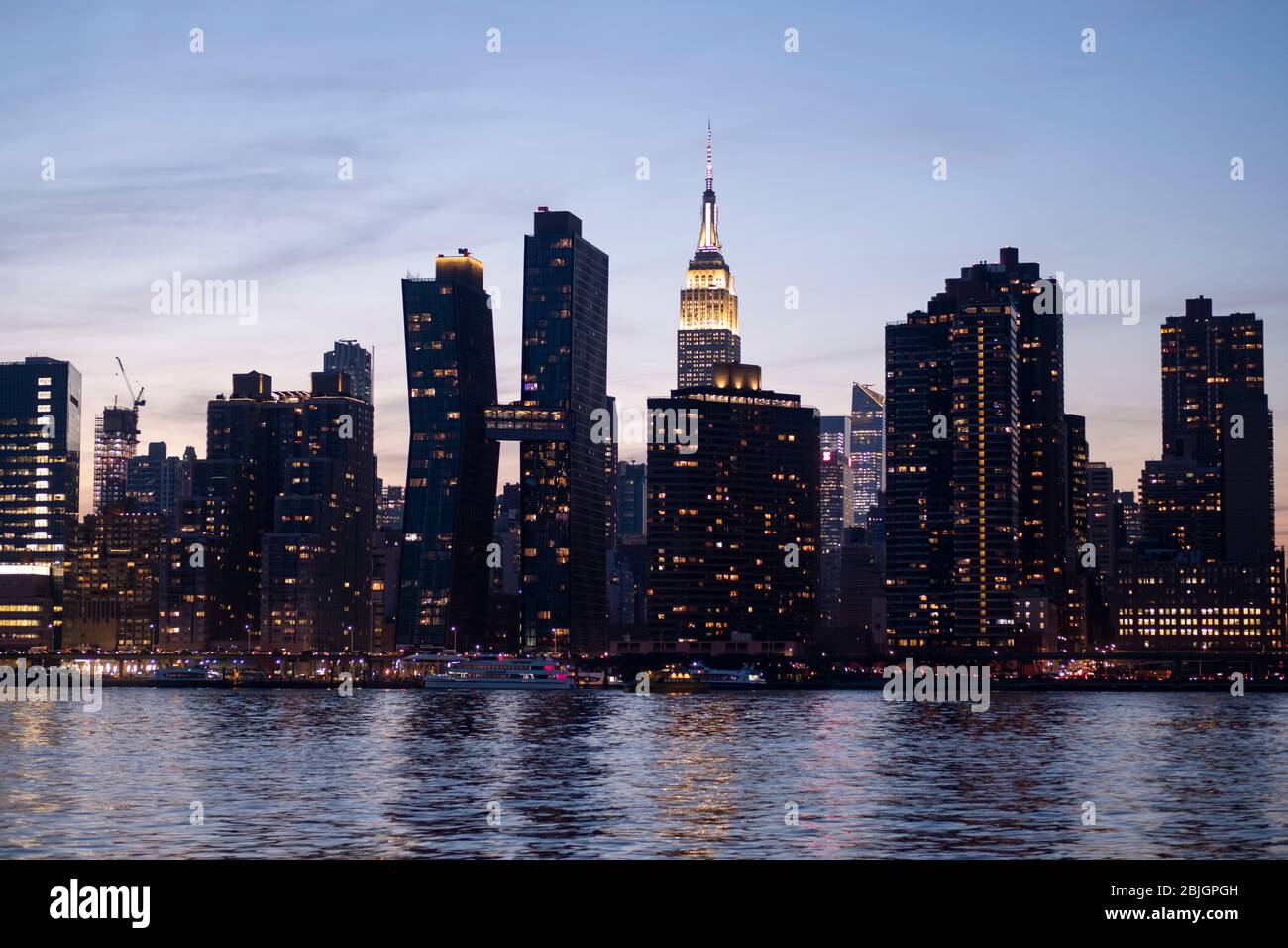 Vue sur le crépuscule de la ligne Skyline de Manhattan avec l'éminent Empire State Building vue de l'East River à New York City Banque D'Images