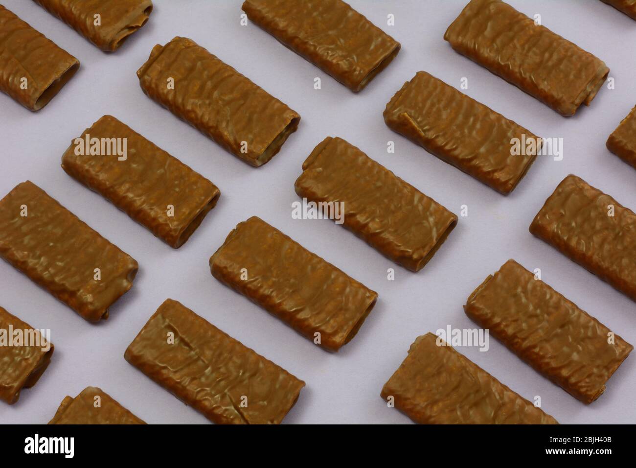 La gaufre de chocolat au lait colle les cookies en rangées sur fond violet lavande Banque D'Images