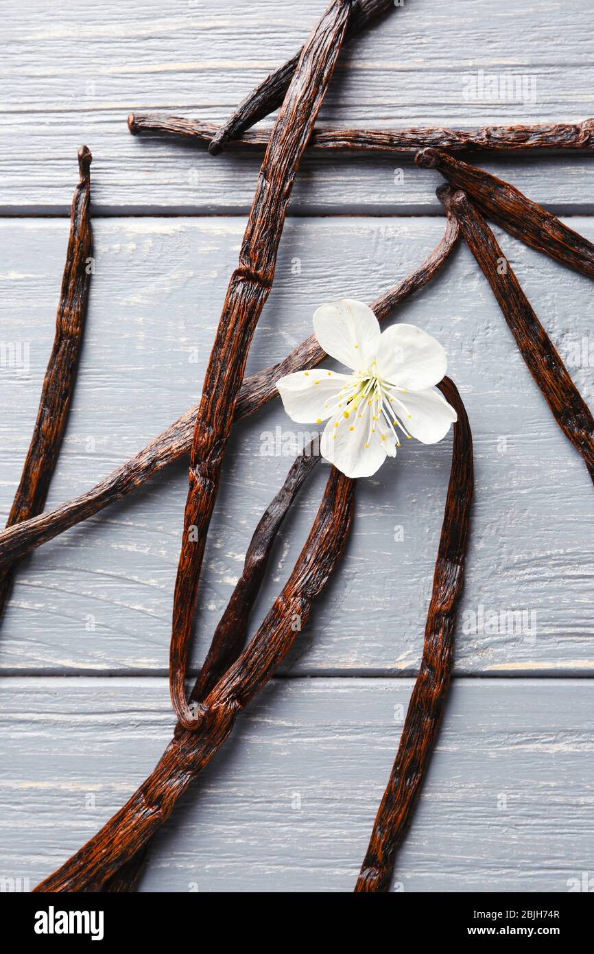Bâtonnets de vanille séchés et fleurs sur fond en bois Banque D'Images