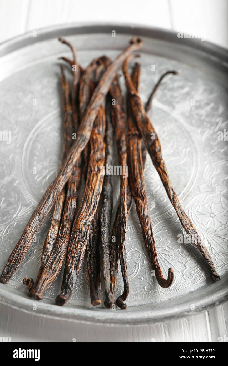 Plaque métallique avec bâtonnets de vanille séchés sur table en bois clair, fermeture Banque D'Images