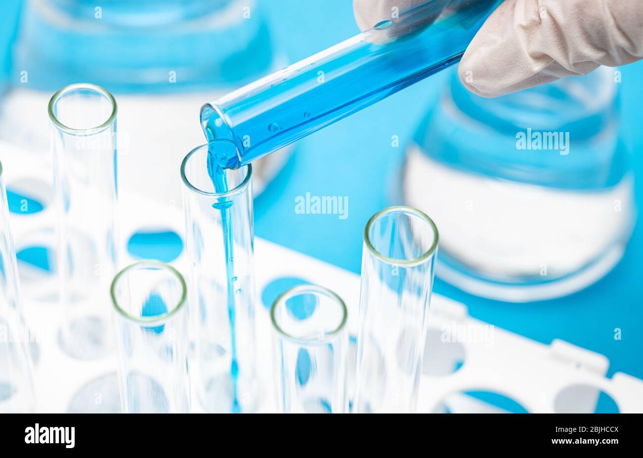 Main d'un chercheur tenant un tube à essai contenant du liquide bleu. Banque D'Images