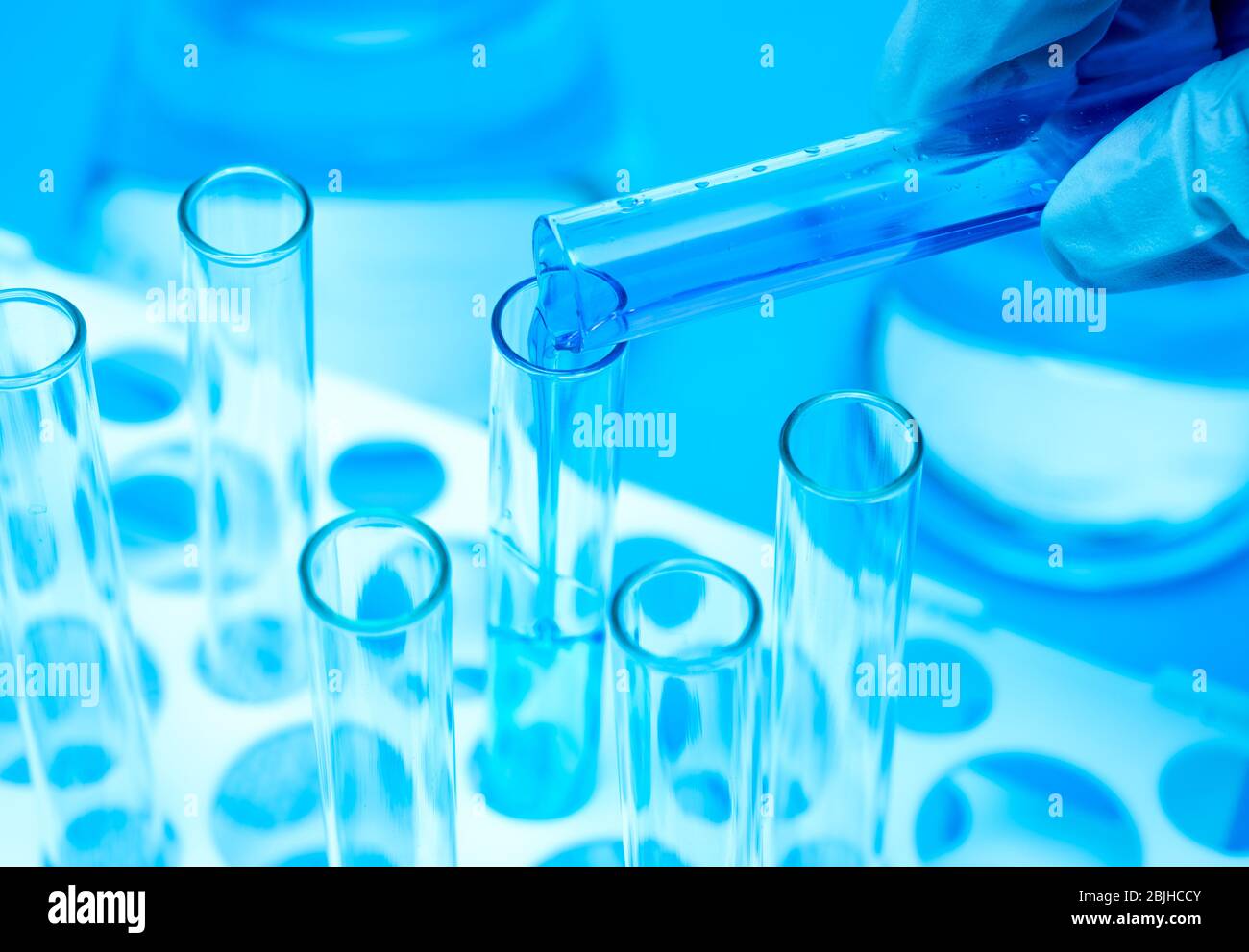 Main d'un chercheur tenant un tube à essai contenant du liquide bleu. Banque D'Images