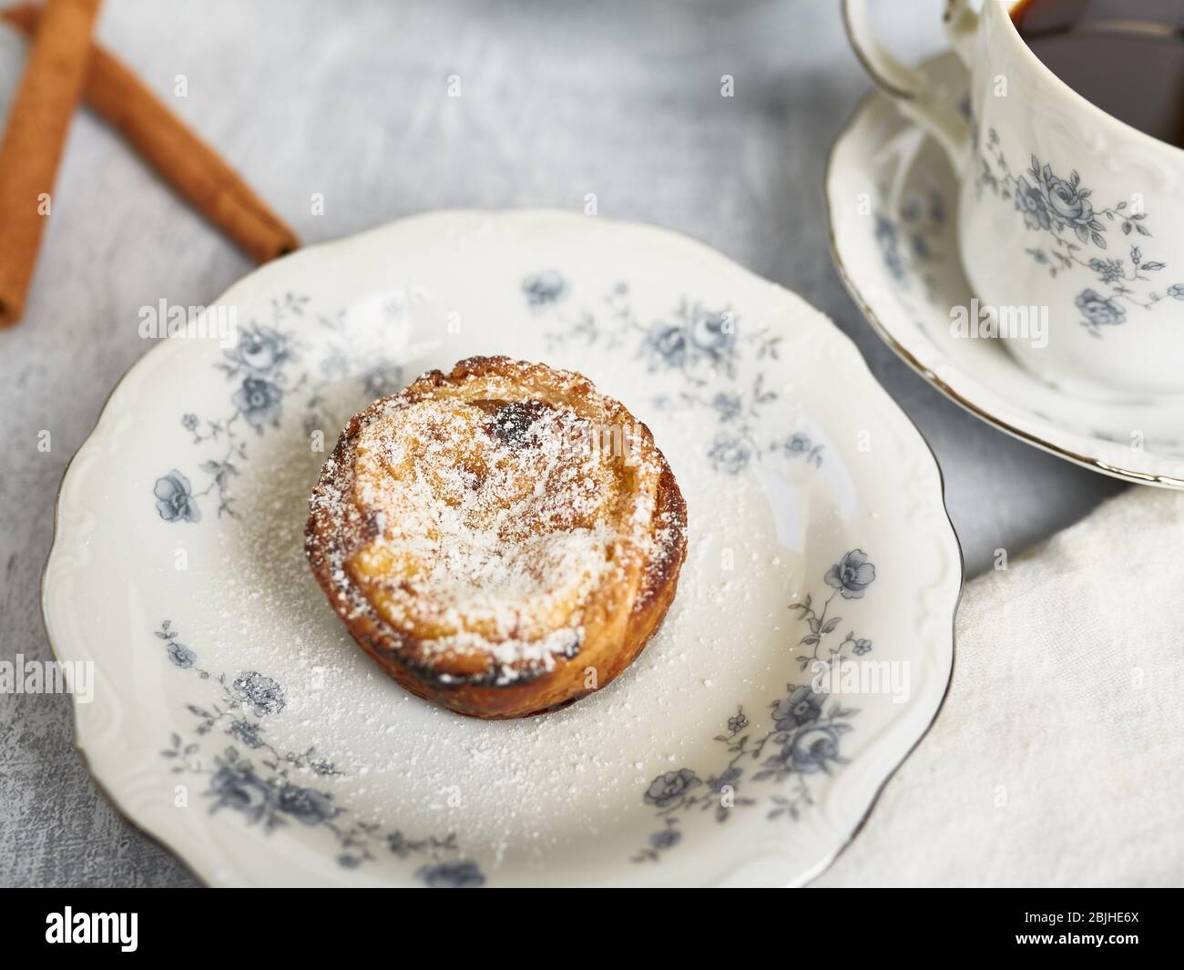 Tartes à œufs portugais frais, Pastais de Nata, servies sur une plaque en porcelaine ancienne avec une tasse de café chaud. Banque D'Images