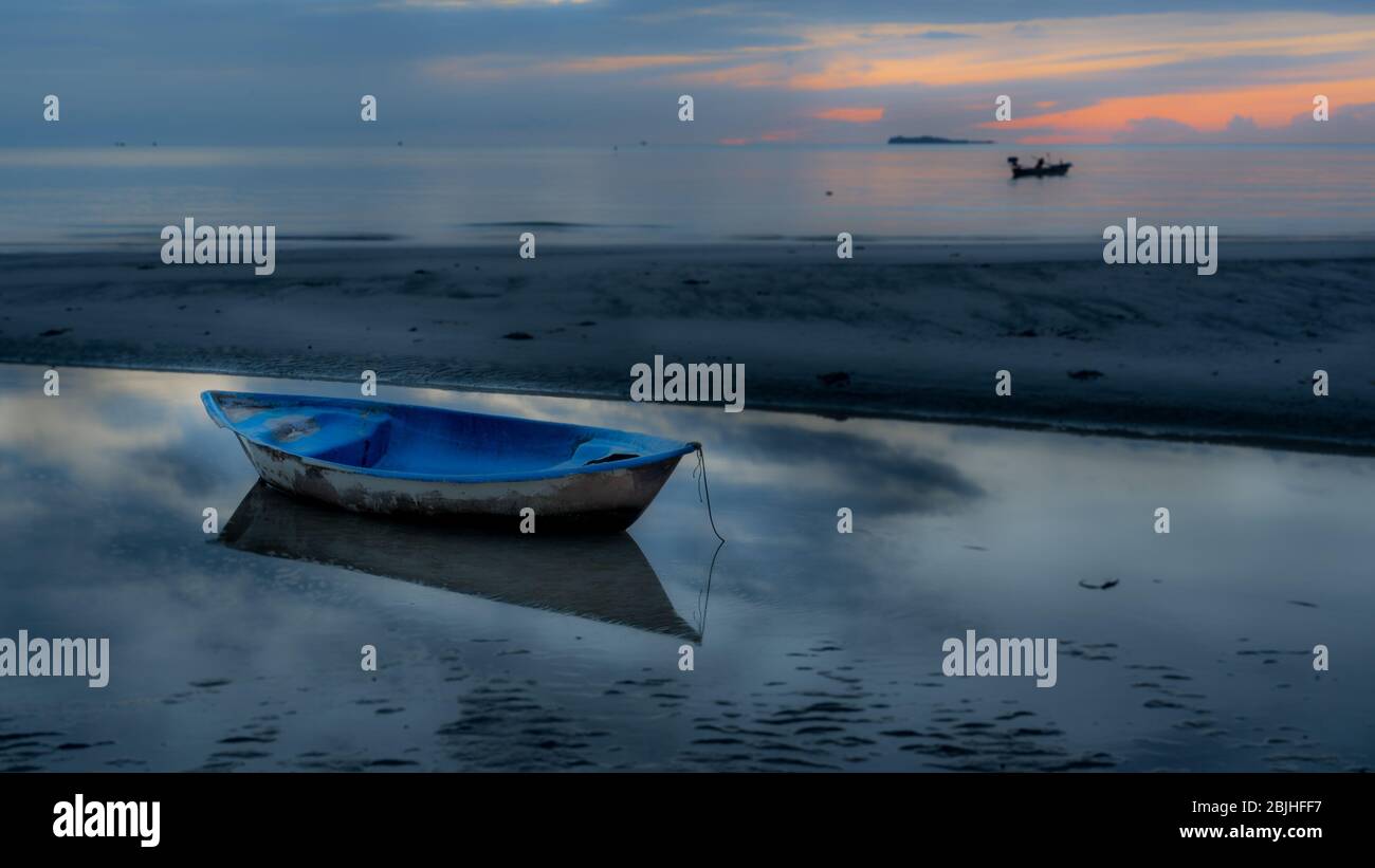 Canot assis dans la piscine à marée basse à la plage au coucher du soleil à Pythiu sur le golfe de Thaïlande Banque D'Images