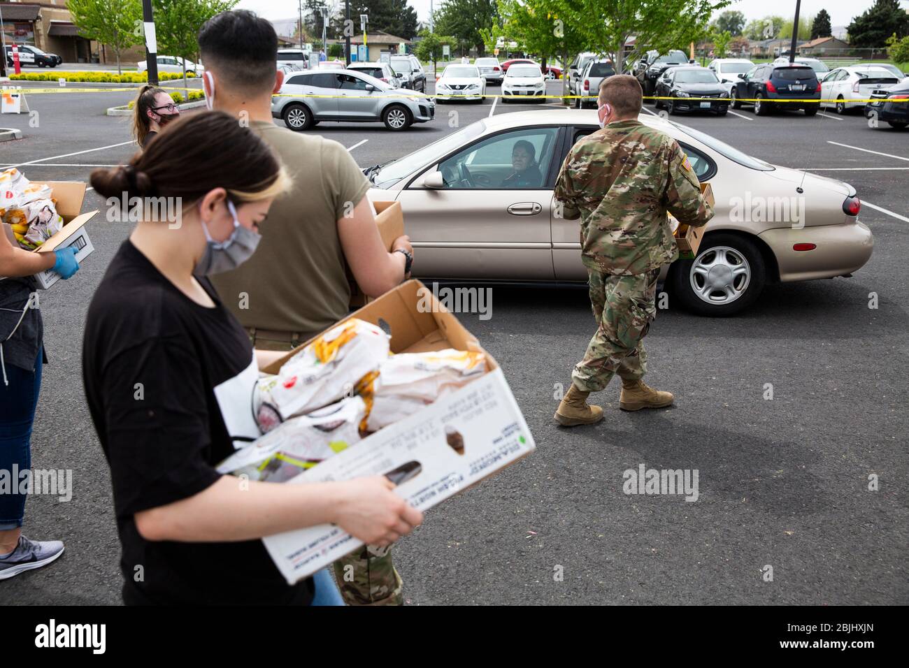Les employés de la clinique des travailleurs agricoles de la vallée de Yakima et les soldats de la Garde nationale de Washington distribuent des boîtes de nourriture gratuite aux résidents sous des impos de l'État Banque D'Images