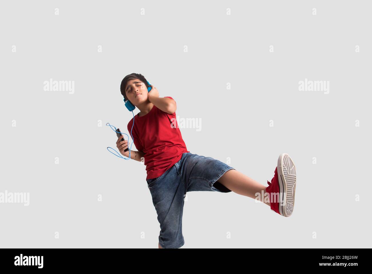 Portrait d'un jeune garçon écoutant de la musique par casque et danser. (Enfants) Banque D'Images