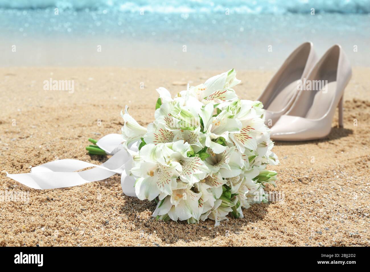 Magnifique bouquet et chaussures à talon haut sur sable. Concept de mariage sur la plage Banque D'Images