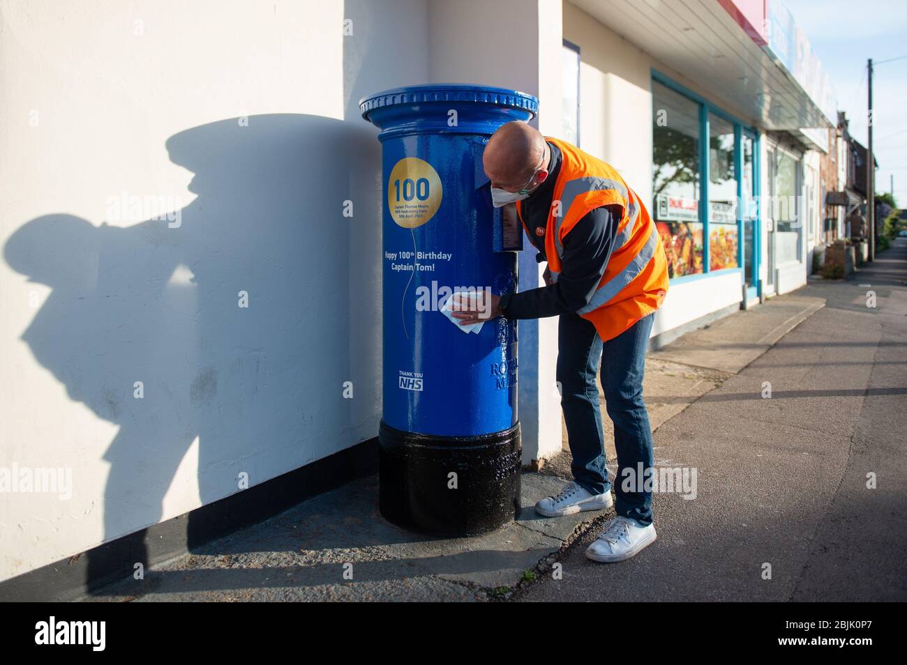 Un homme polit une boîte de lettres peinte en bleu pour marquer le 100ème anniversaire du vétéran de la seconde Guerre mondiale, le capitaine Tom Moore, près de la maison de Marston Morelaine, près de Bedford. Banque D'Images