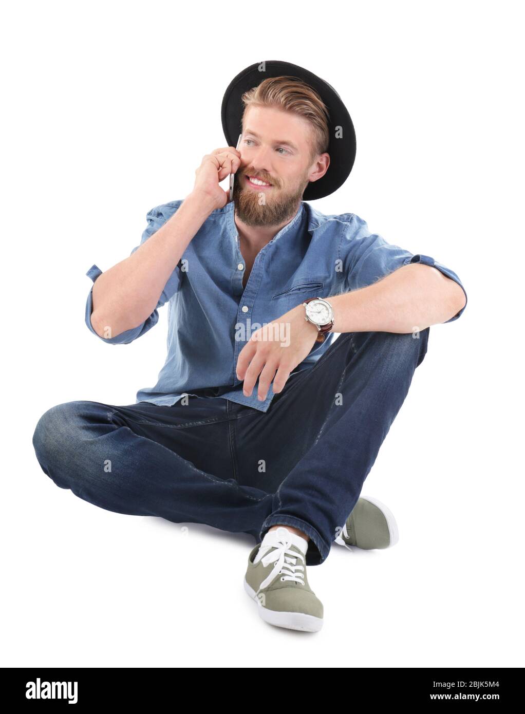 Jeune homme hipster parlant au téléphone sur fond blanc Banque D'Images