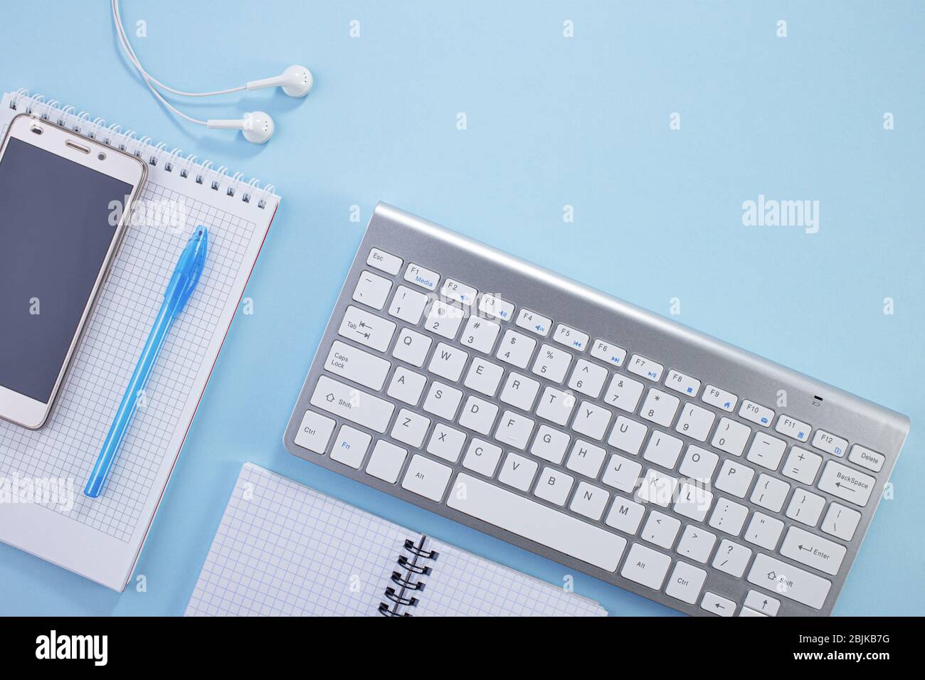 Espace de travail minimal. Photo créative à plat du bureau. Bureau avec vue sur le dessus avec bloc-notes, clavier, bloc-notes en papier et fournitures de couleur bleue b Banque D'Images