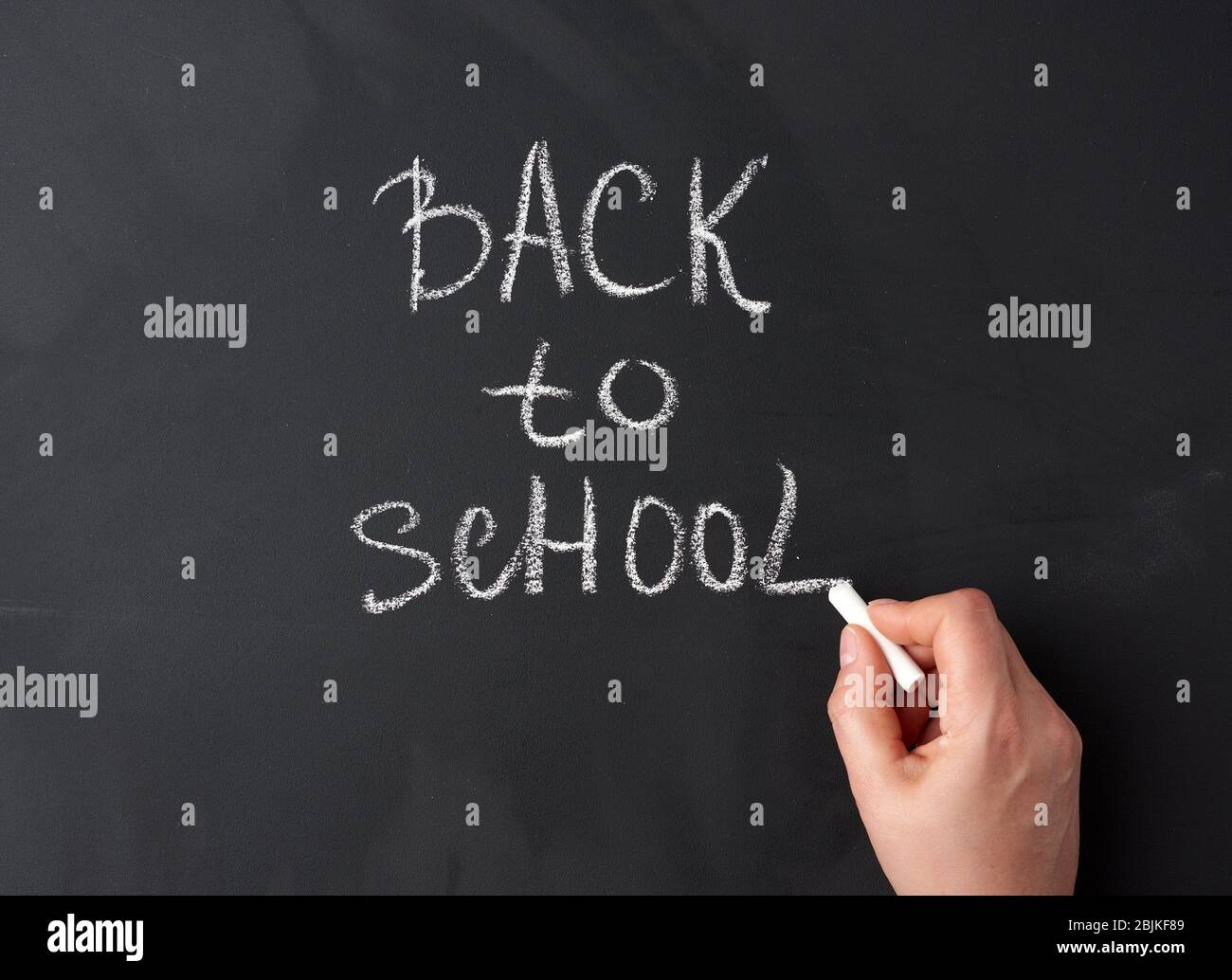 craie blanche de retour à l'école sur le tableau noir, la main tient un  morceau de craie blanche, gros plan Photo Stock - Alamy