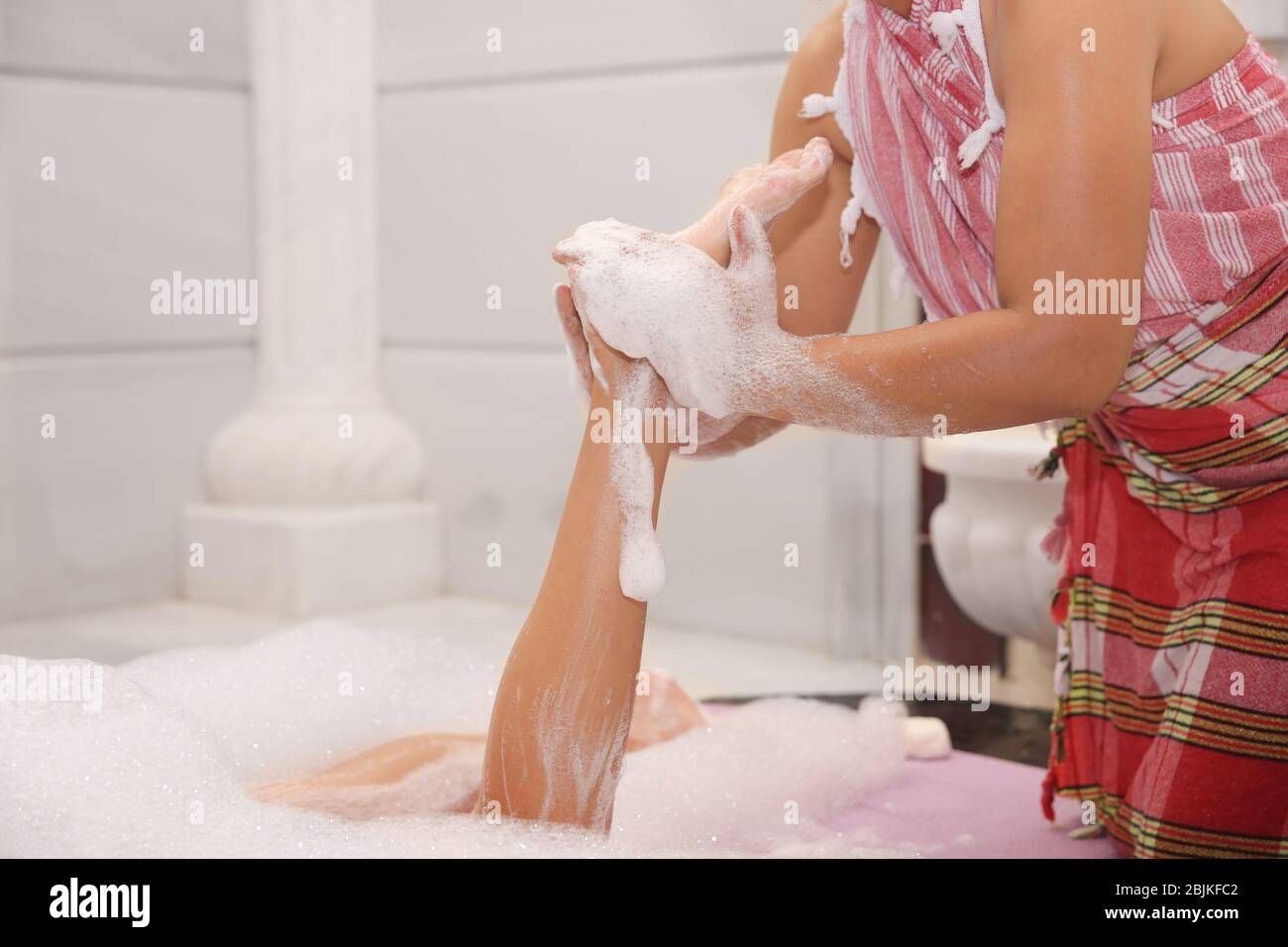Femme ayant un massage en mousse au hammam Banque D'Images