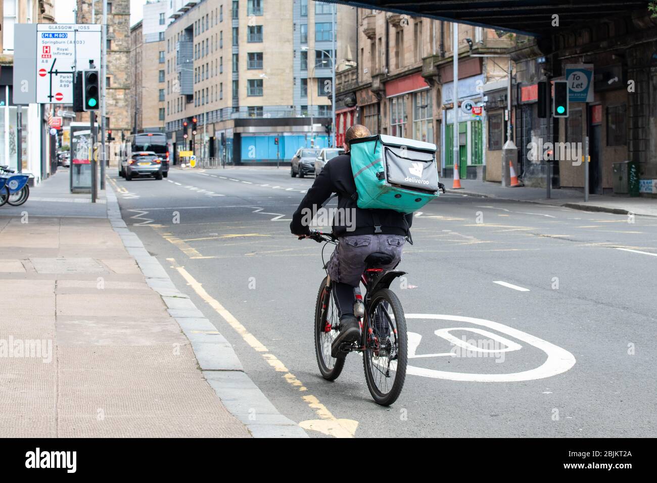 Le pilote Deliveroo se faisant du vélo dans les rues presque désertes de Glasgow pendant le verrouillage du coronavirus, Glasgow, Écosse, Royaume-Uni Banque D'Images