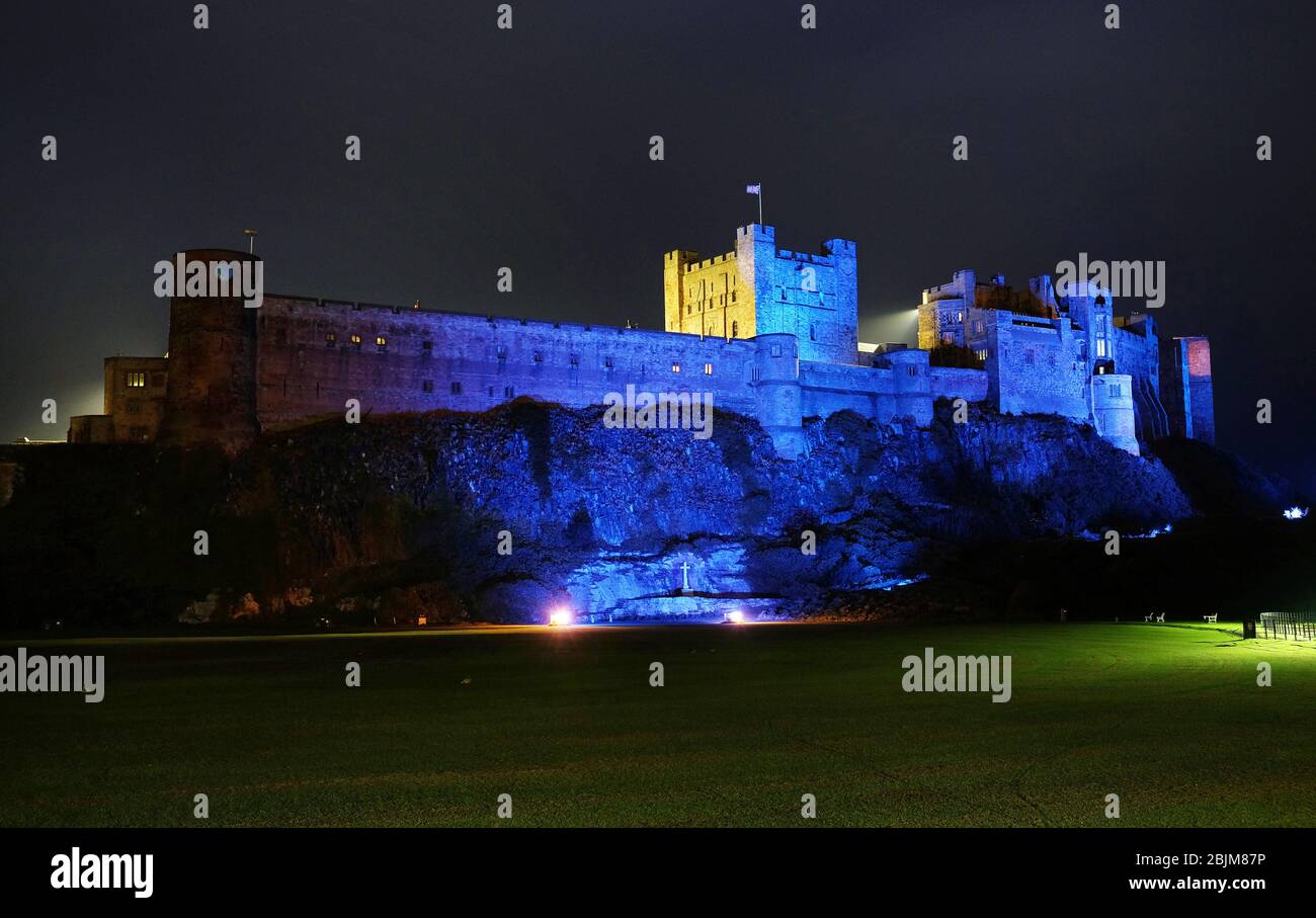 Forteresse côtière le château de Bamburgh dans Northumberland est devenu bleu en l'honneur des travailleurs et des soignants du NHS qui combattent la pandémie de coronavirus mercredi soir. Le personnel d'entretien du château privé, qui a passé des semaines à travailler sur une solution aux illuminations bleues, allumerait à nouveau le château ce soir pour le clap du jeudi pour les carers. Banque D'Images