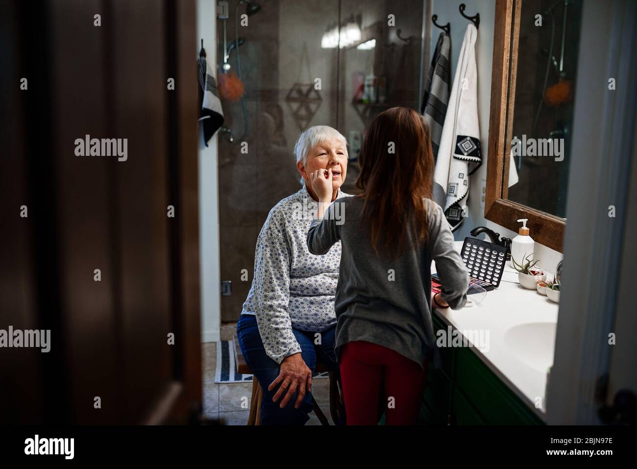 Une fille qui met du maquillage sur sa grand-mère Banque D'Images