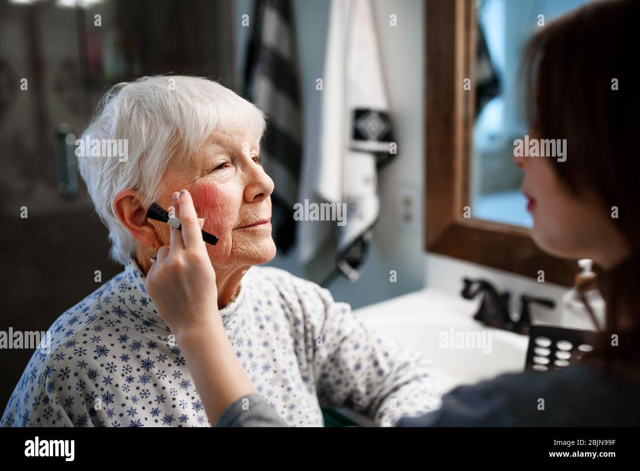 Une fille qui met du maquillage sur sa grand-mère Banque D'Images