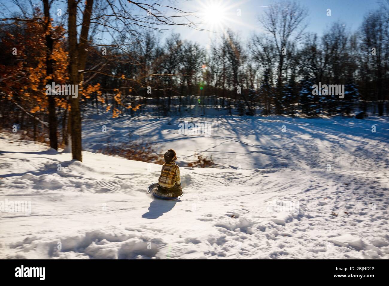 Garçon en traîneau à une colline dans la neige, États-Unis Banque D'Images