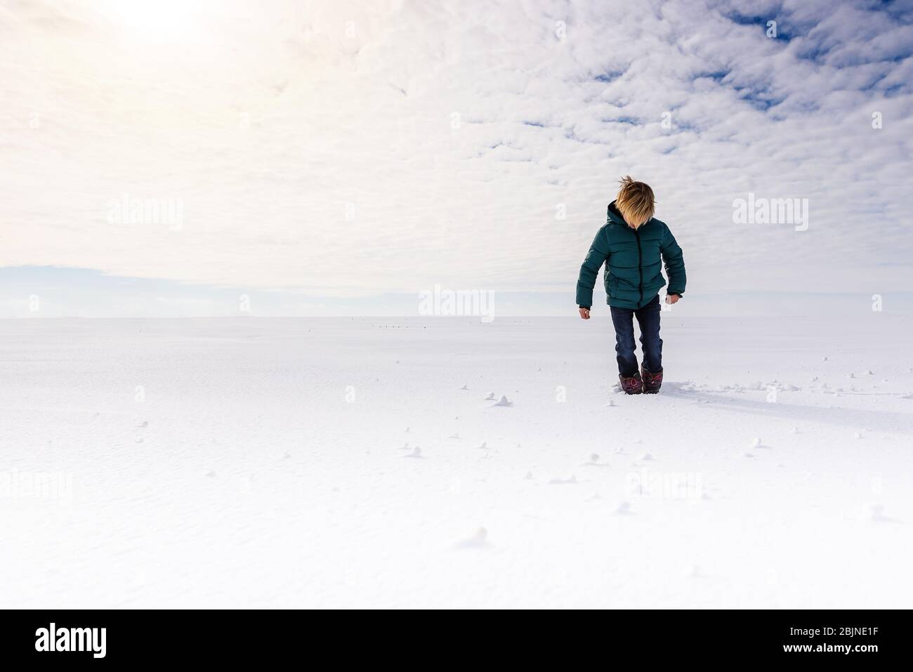 Garçon marchant dans un champ enneigé, États-Unis Banque D'Images