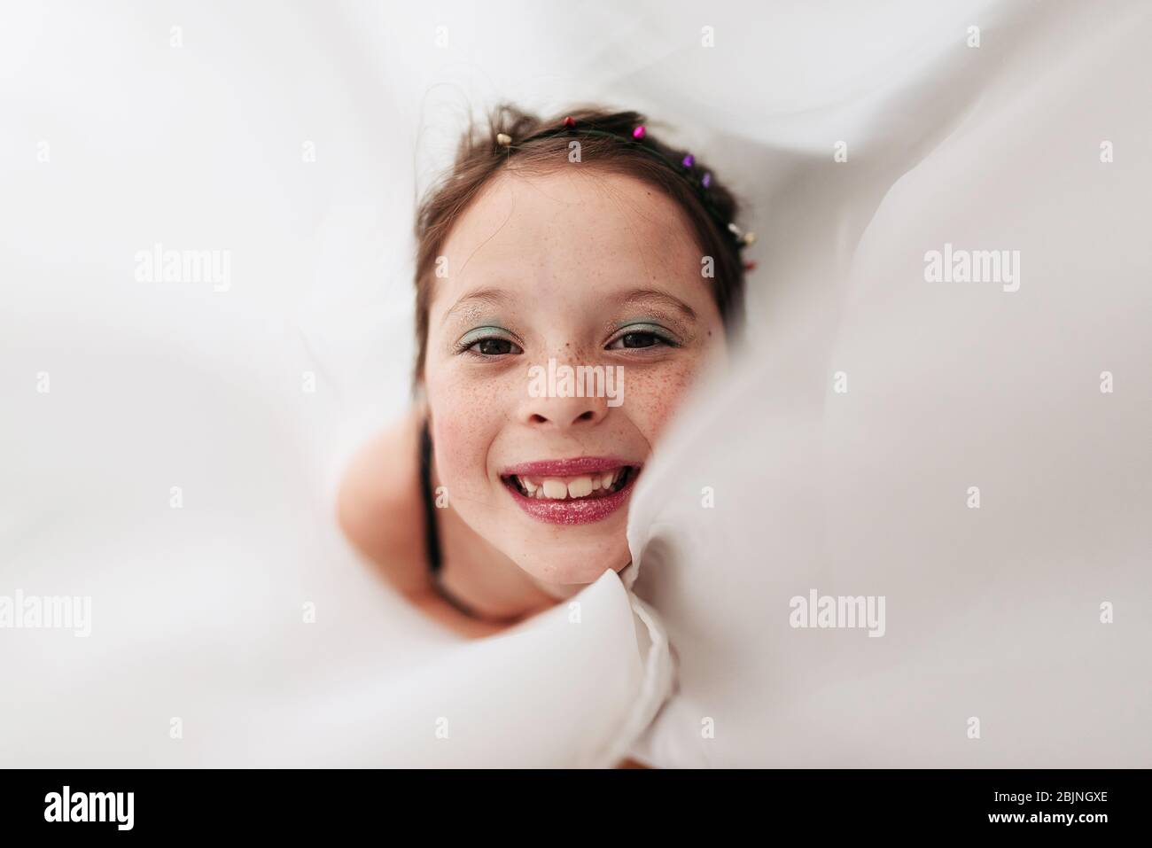 Portrait d'une jeune fille portant un maquillage enveloppé dans un rideau Banque D'Images
