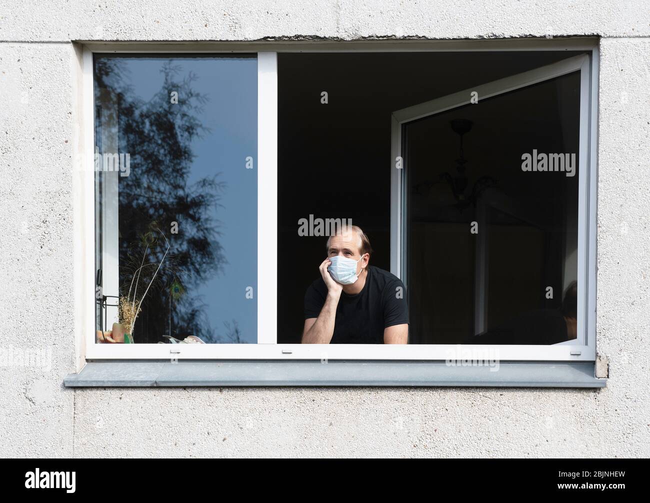 Homme portant un masque de visage regardant par une fenêtre, Lituanie Banque D'Images