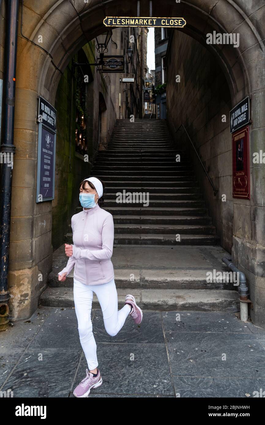Jogging féminin portant un masque de visage à court de Fleshmarket vide Fermer pendant le verrouillage du coronavirus à Edinburgh Old Town, Écosse, Royaume-Uni Banque D'Images