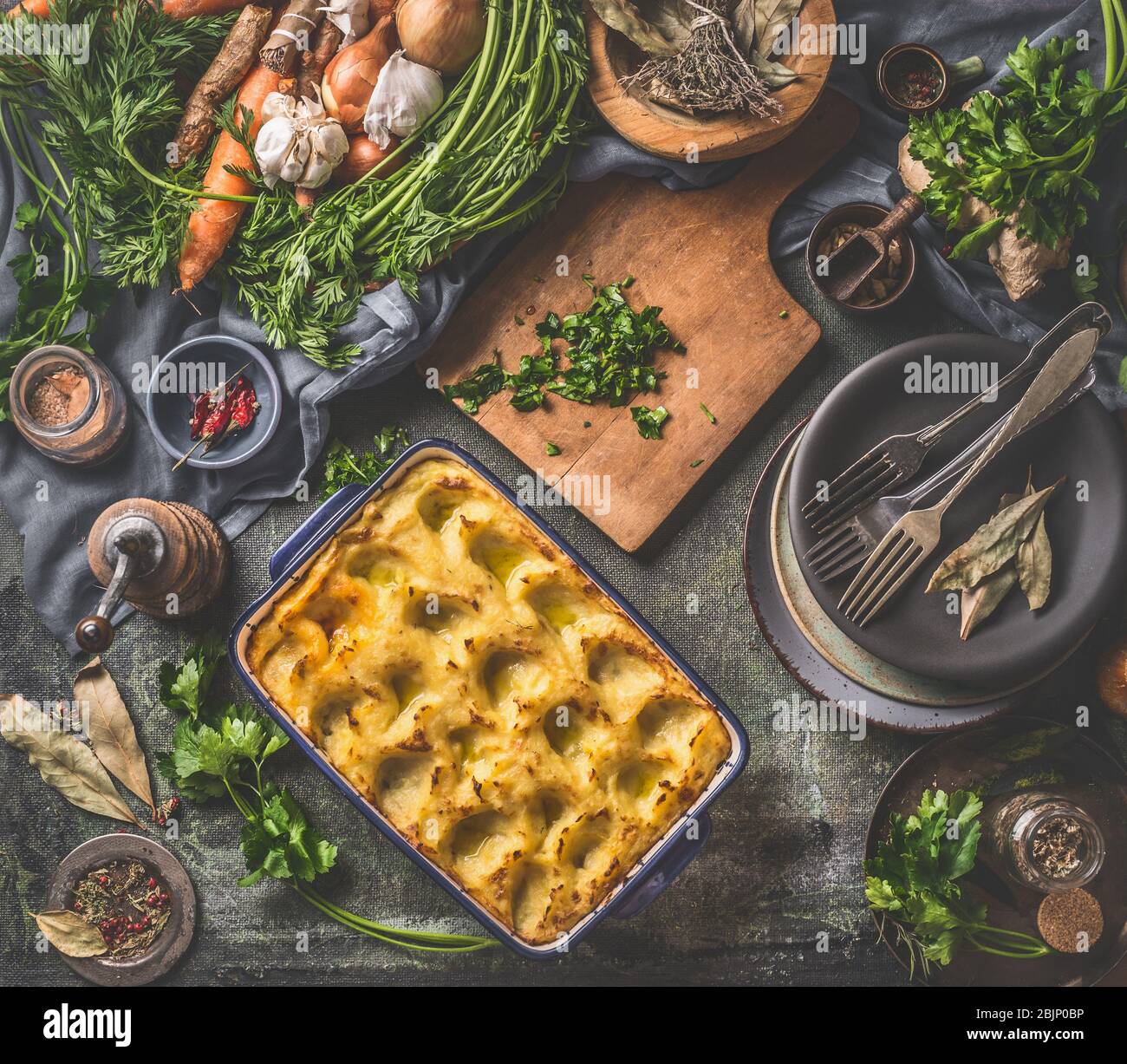 Purée de pommes de terre cuite dans une casserole avec cuillère sur fond sombre rustique de table de cuisine avec ingrédients et ustensiles vintage. Vue de dessus. Cuisine maison savoureuse Banque D'Images