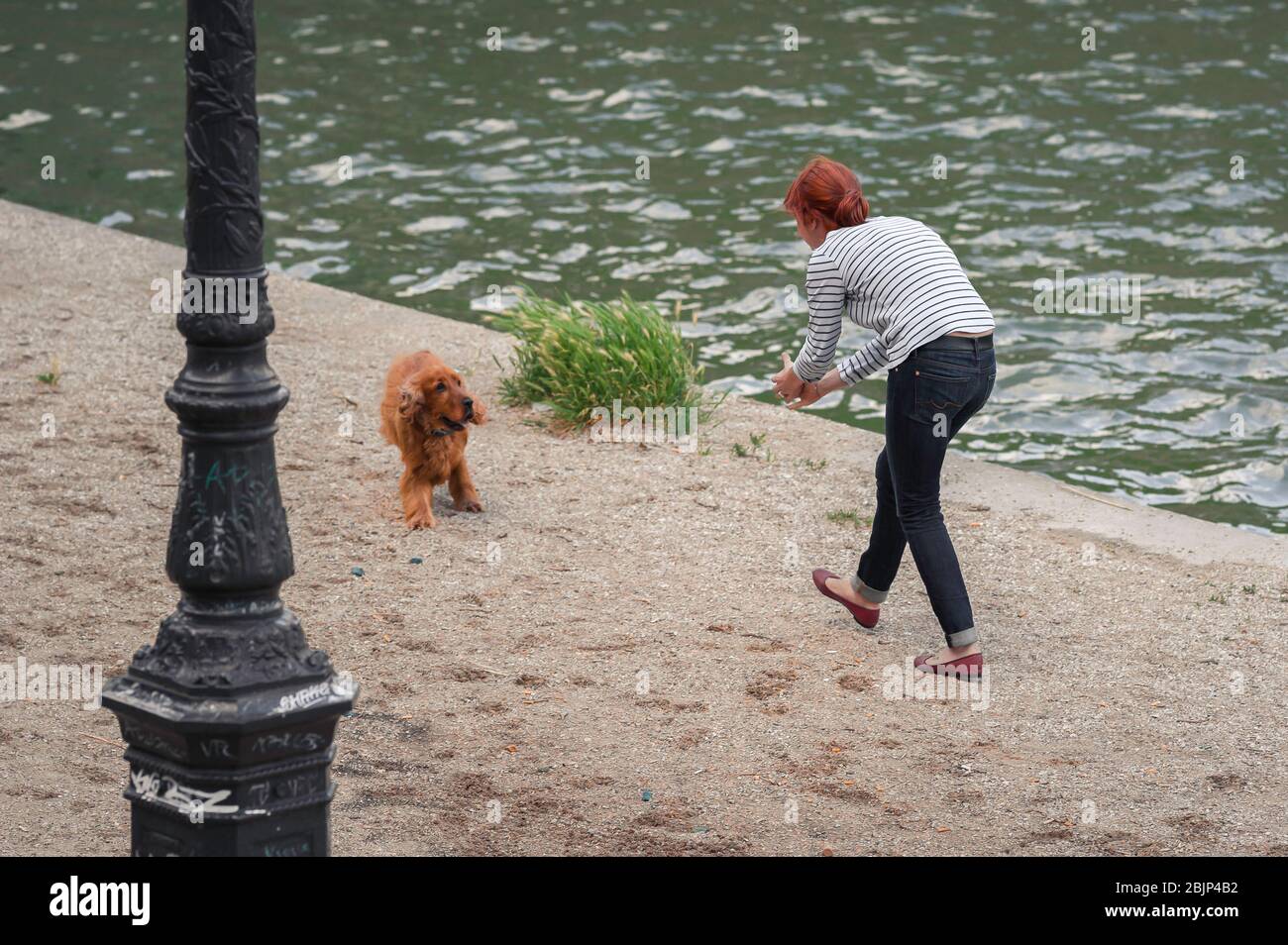 Chien de femme, vue d'une jeune femme française jouant avec son chien le long du Quai de Valmy dans le centre de Paris, France Banque D'Images