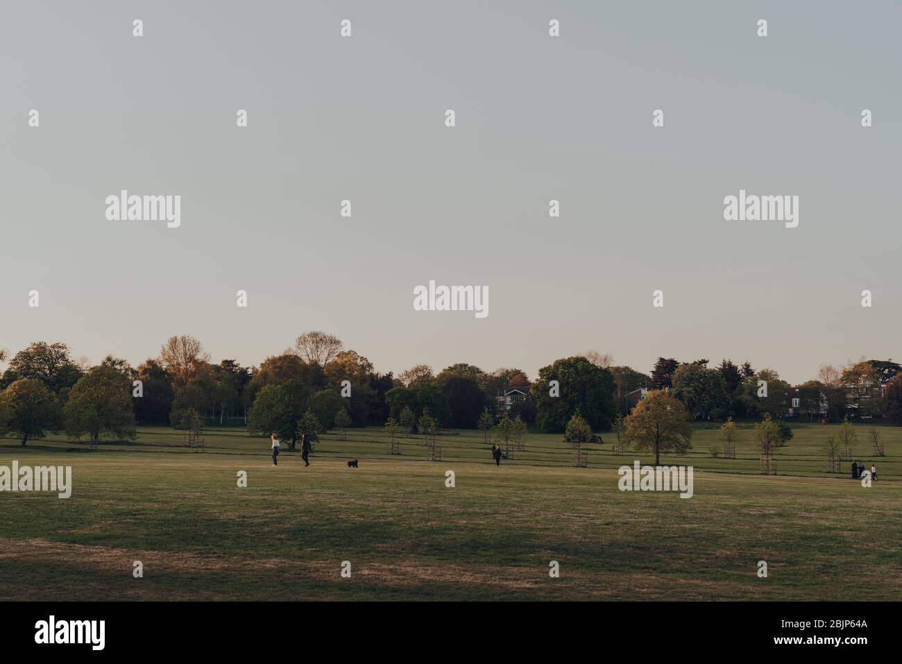 Londres, Royaume-Uni - 22 mars 2020: Vue lointaine des gens marchant dans le parc Broomfield, parc public à Palmers Green dans le quartier londonien d'Enfield, Royaume-Uni, dur Banque D'Images