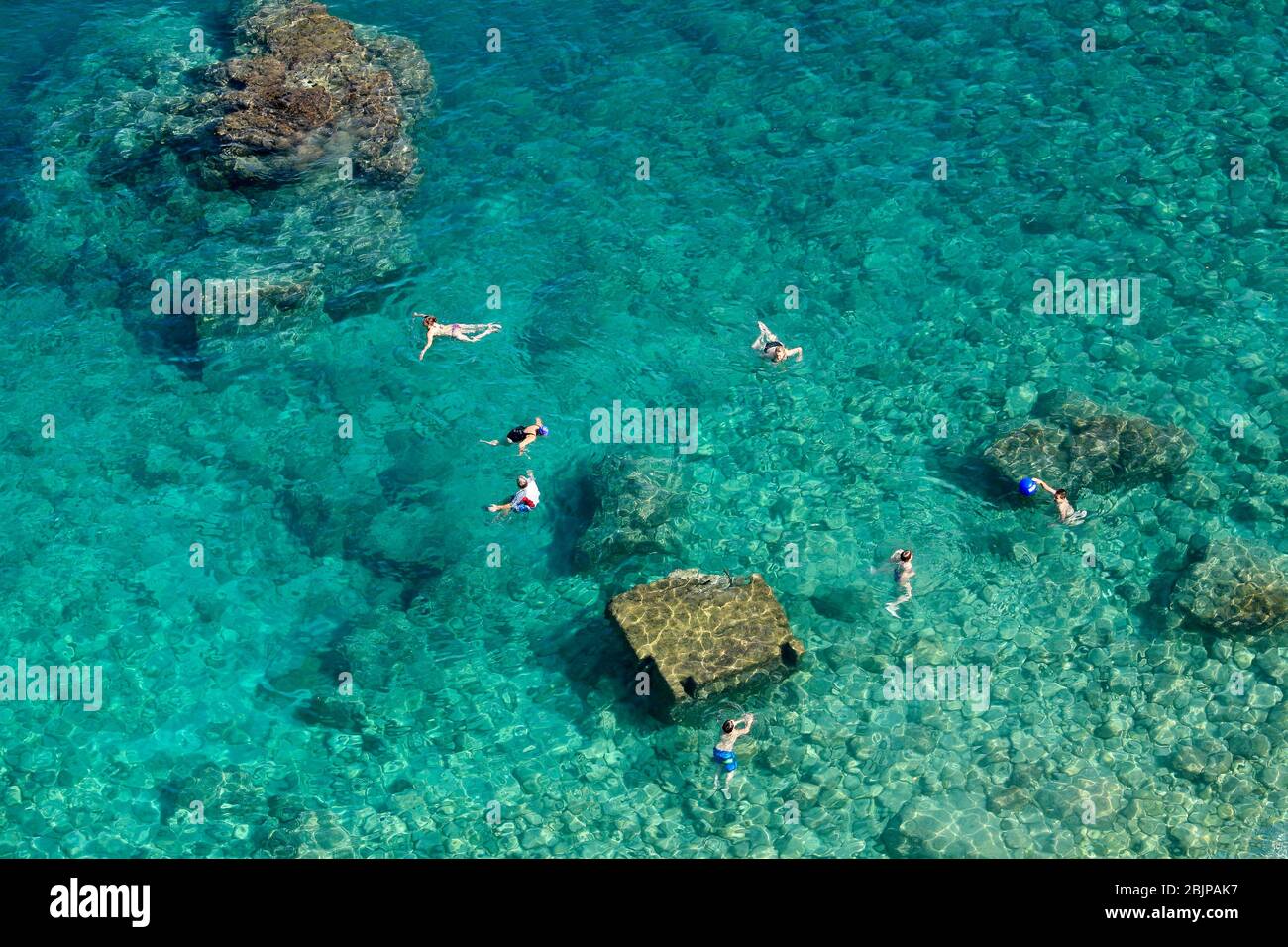 Les garçons nagent entre les pierres près des falaises abruptes de la côte Adriatique sur la plage de Bellevue, à l'extérieur de la vieille ville de Dubrovnik. Banque D'Images