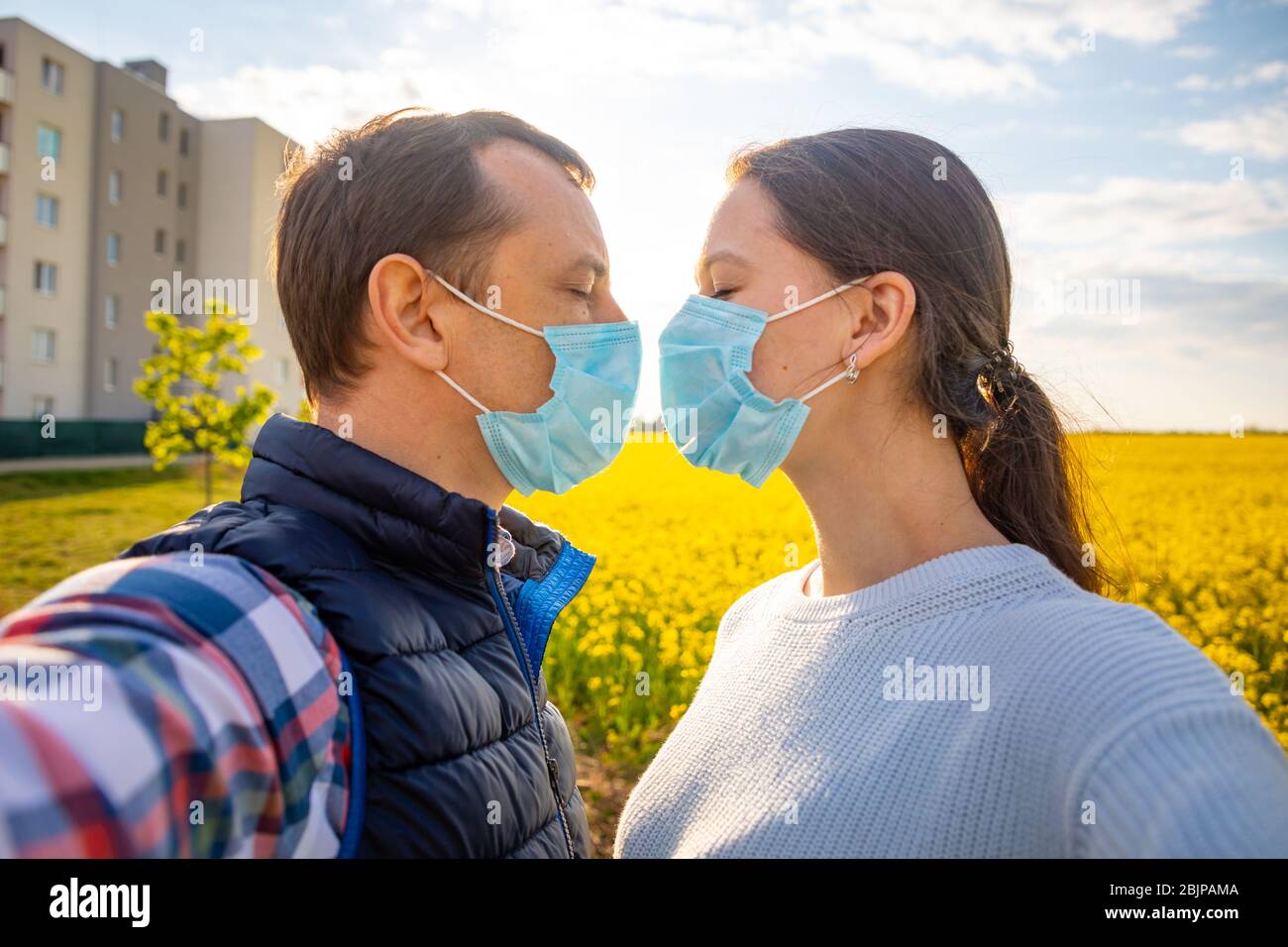 L'homme et la femme s'embrassent dans un masque médical protecteur sur le visage à la campagne Banque D'Images