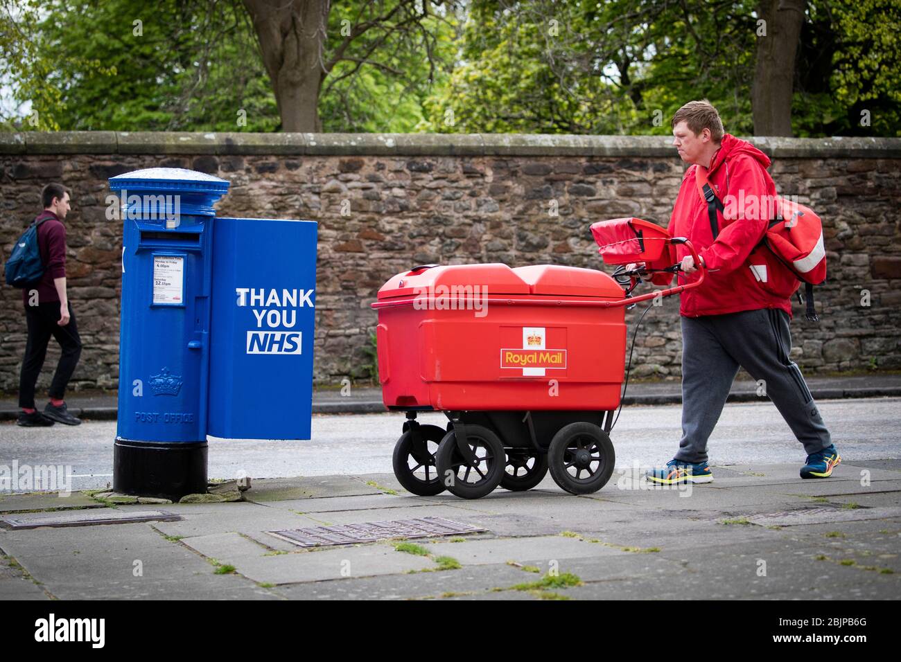 Le Postman Graeme Byers passe par l'une des boîtes de poste spécialement décorées à Édimbourg peint en bleu à l'appui des travailleurs et des soignants du NHS qui luttent contre la pandémie de coronavirus. Banque D'Images